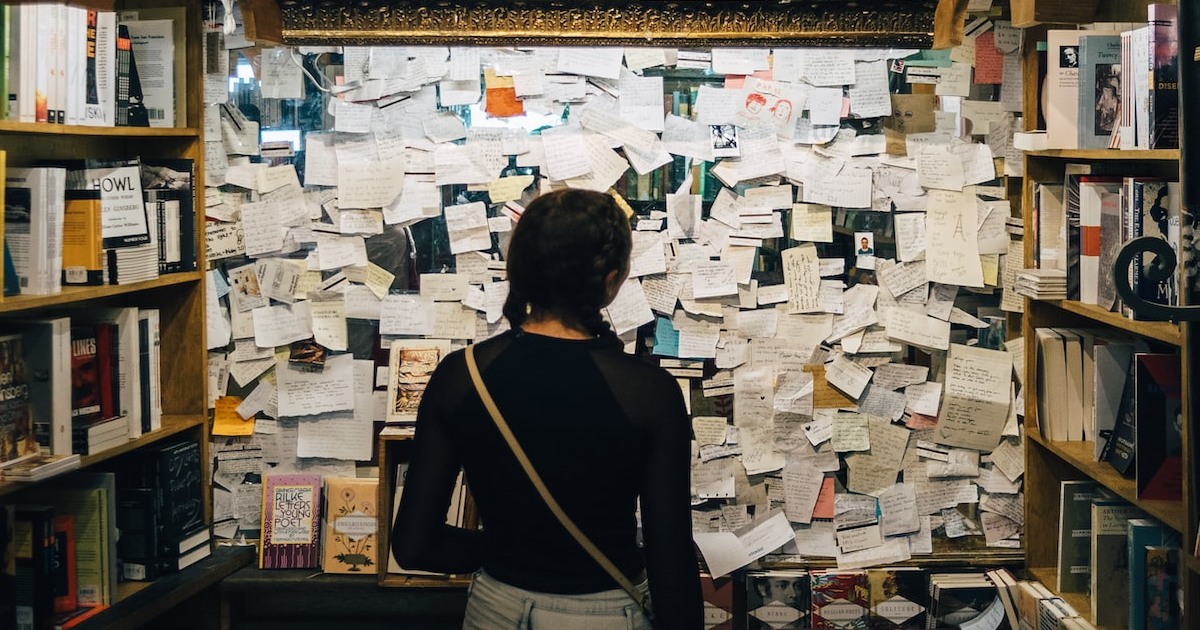 A woman standing in front of a bulletin board covered in notes
