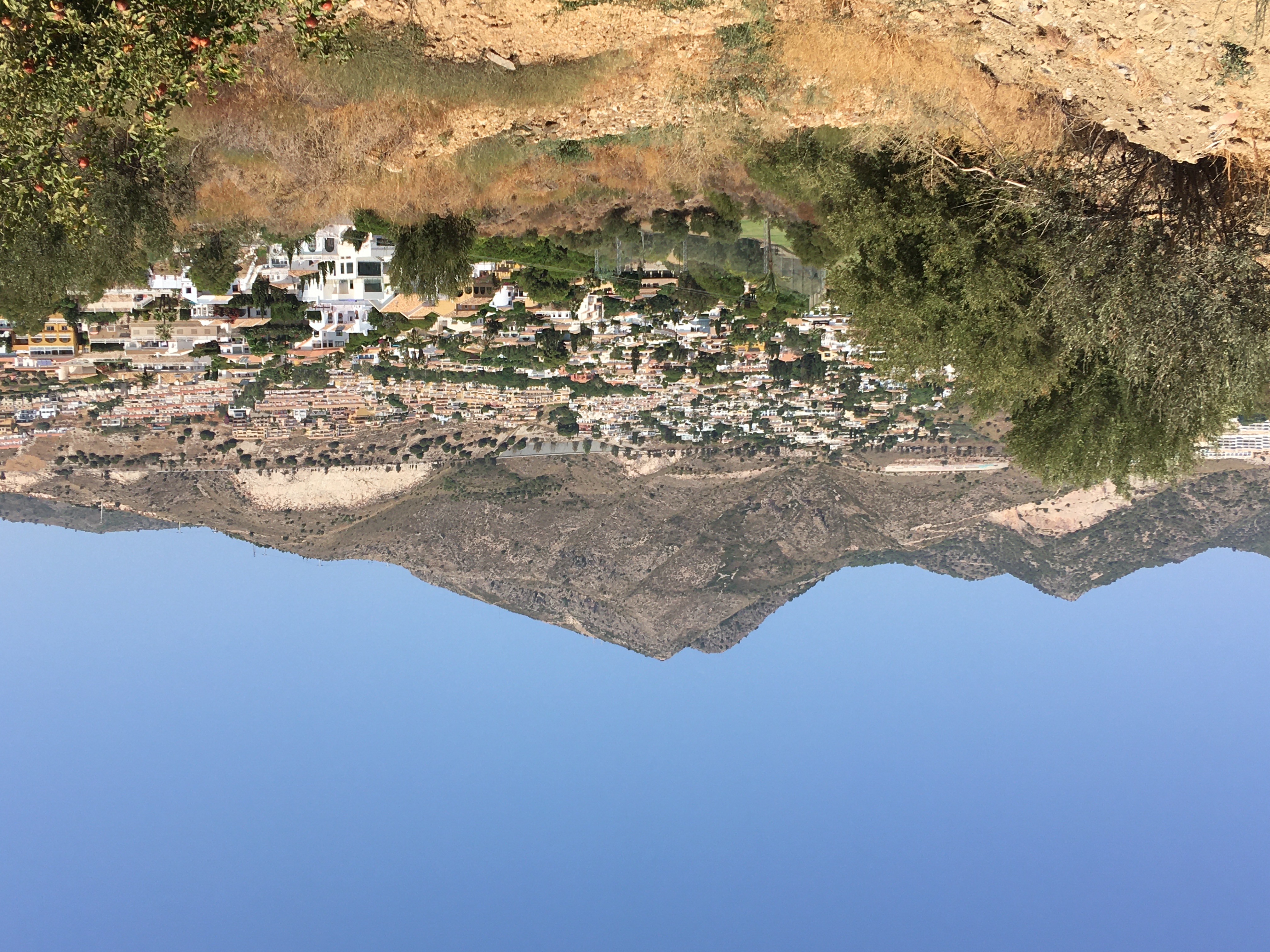 An arid landscape with a small village nestled in a valley with a mountain in the background