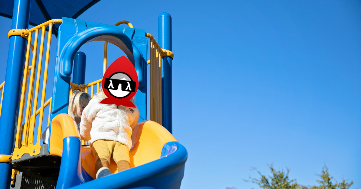A child with the Babashka logo as a face on a playground slide