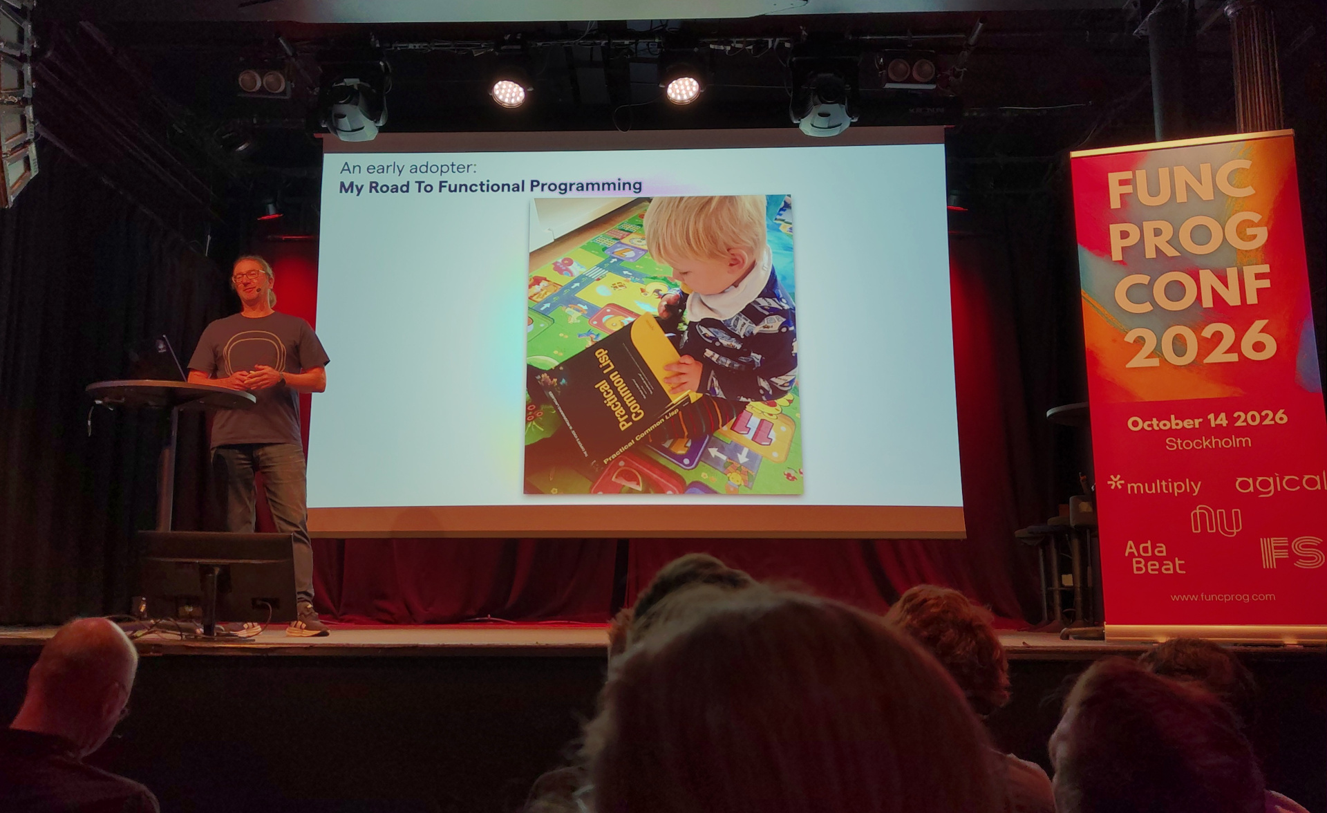 A toddler holding a copy of the "Practical Common Lisp" book