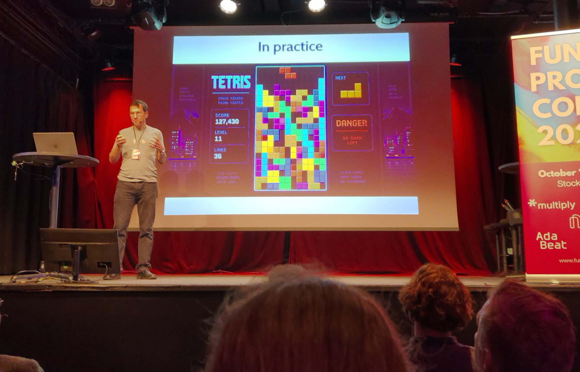 Eric presents a slide labelled "In practice", showing a game of Tetris about to be lost